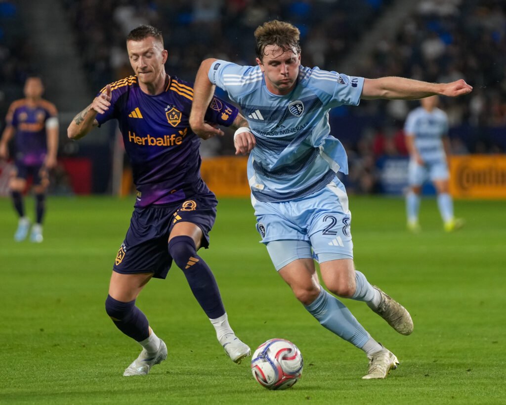 Marco Reus of the LA Galaxy battles for possession with Wyatt Meyer of Sporting Kansas City during an MLS match at Dignity Health Sports Park in Carson, California on March 14, 2026. Photo Credit: Angel Almada