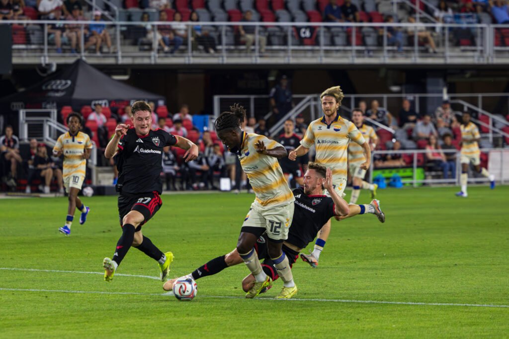 One Knoxville SC's Braudílio Pina Rodrigues being pressured by DC United's Nikola Markovic (27) and Kye Rowles (15) in a clean tackle in the Lamar US OPEN Cup at Audi Field in Washington DC on April 15th, 2026 - Photo Credits - Omar Yair Soto with LAMomentum