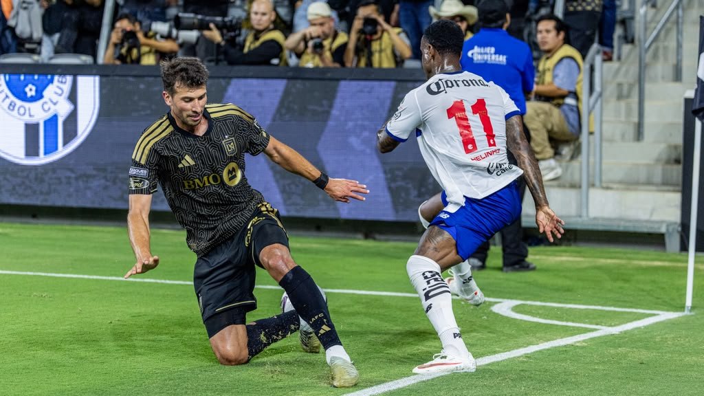 LAFC defender slides in on a tackle near the corner flag as Toluca's Helinho attempts to cut past him.