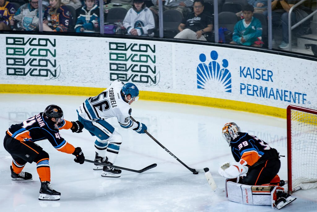 San Jose Barracuda forward Ethan Cardwell (#56) battles for the puck against a San Diego Gulls defender near the goal.