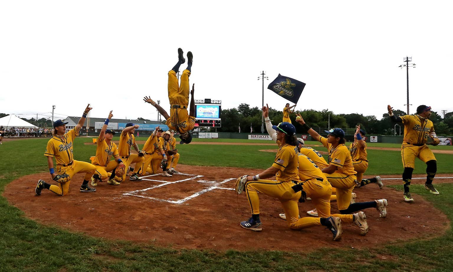 A Savannah Bananas player does a backflip as teammates celebrate on the field