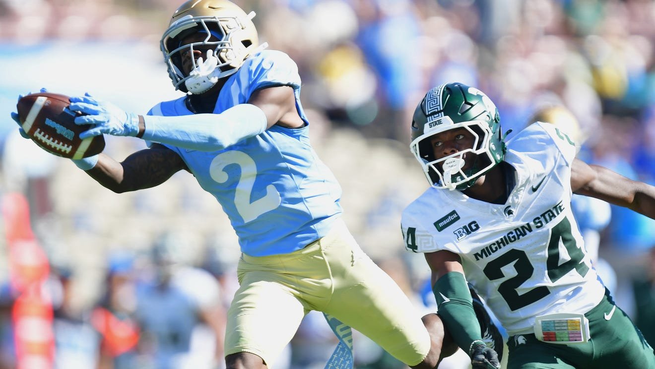 UCLA receiver catching a pass against a Michigan State defender at the Rose Bowl
